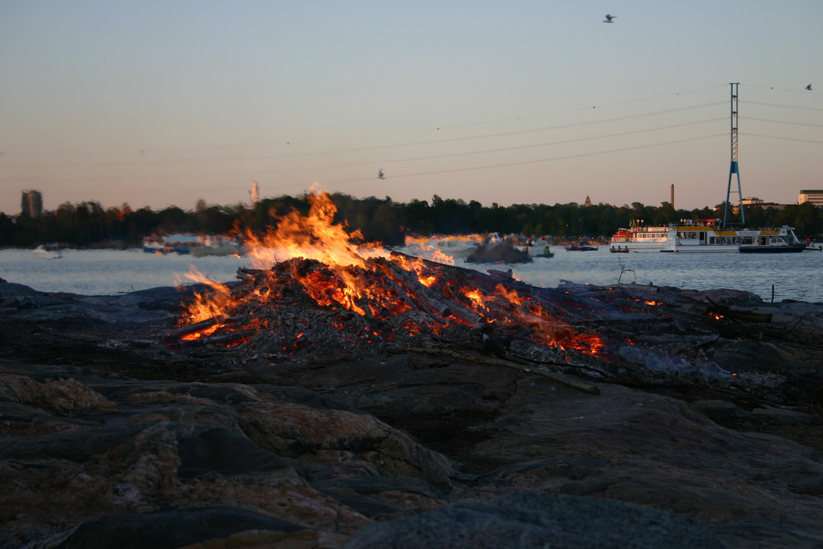 A smaller bonfire on shore..